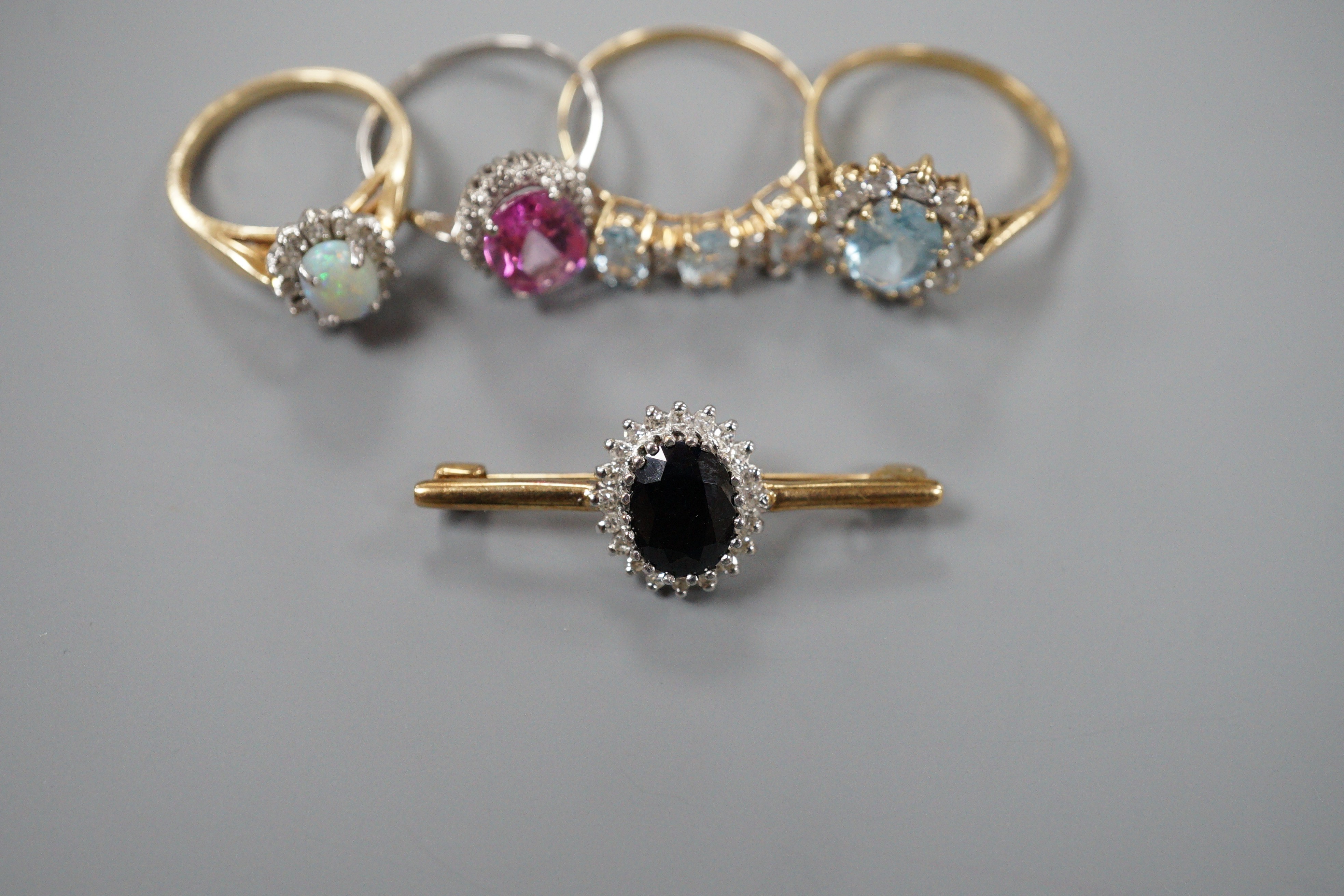 A modern 9ct gold, sapphire and diamond oval cluster set bar brooch, 34mm, gross weight 2.4 grams, a modern 9ct gold and gem set oval cluster ring, gross 2.2 grams, two modern 10k and gem set dress rings, gross weight 3